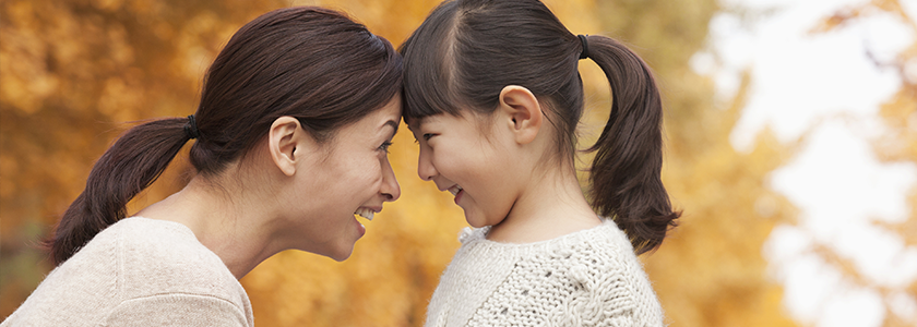 Mother touching her forehead to her daughter's. Both are smiling at each other.